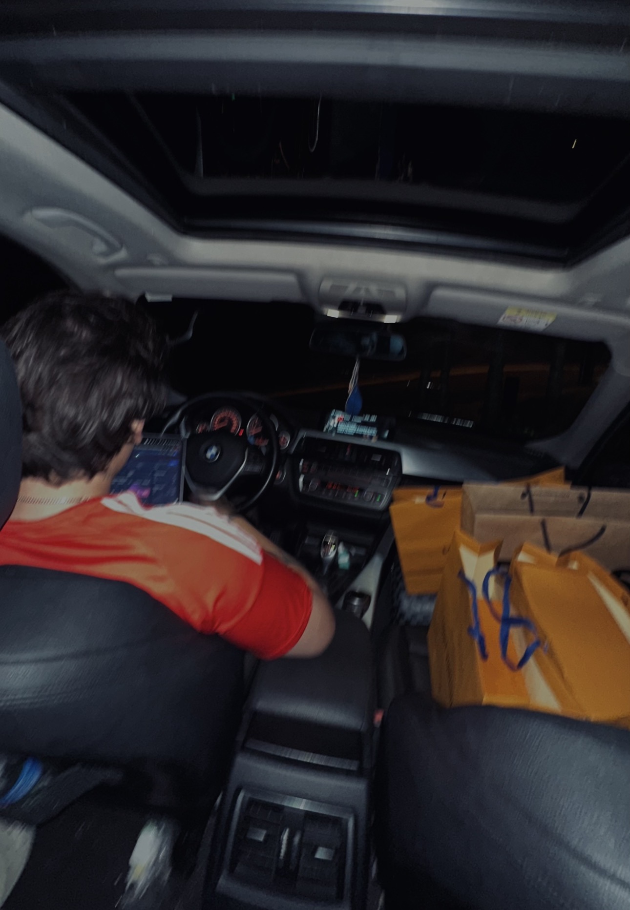 Masson trabalhando no notebook dentro do carro, à noite