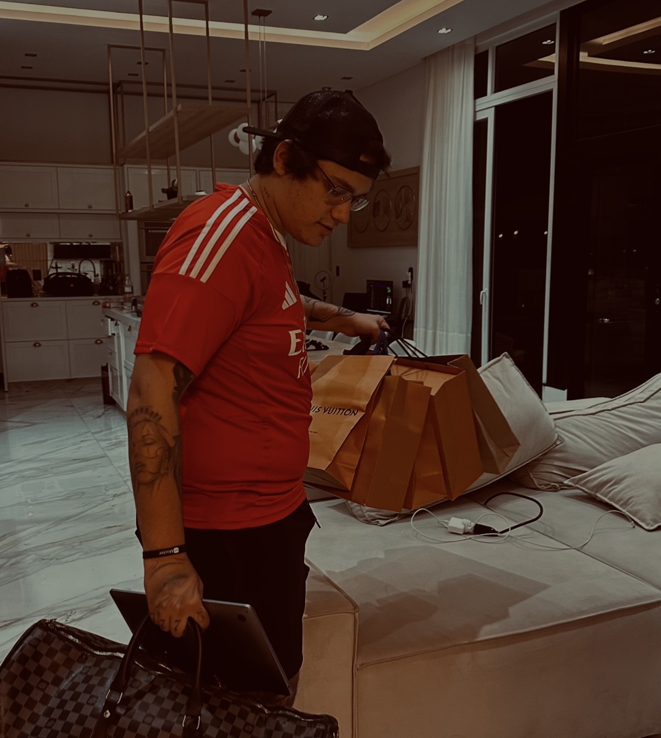 Masson em casa com sacolas Louis Vuitton e o notebook